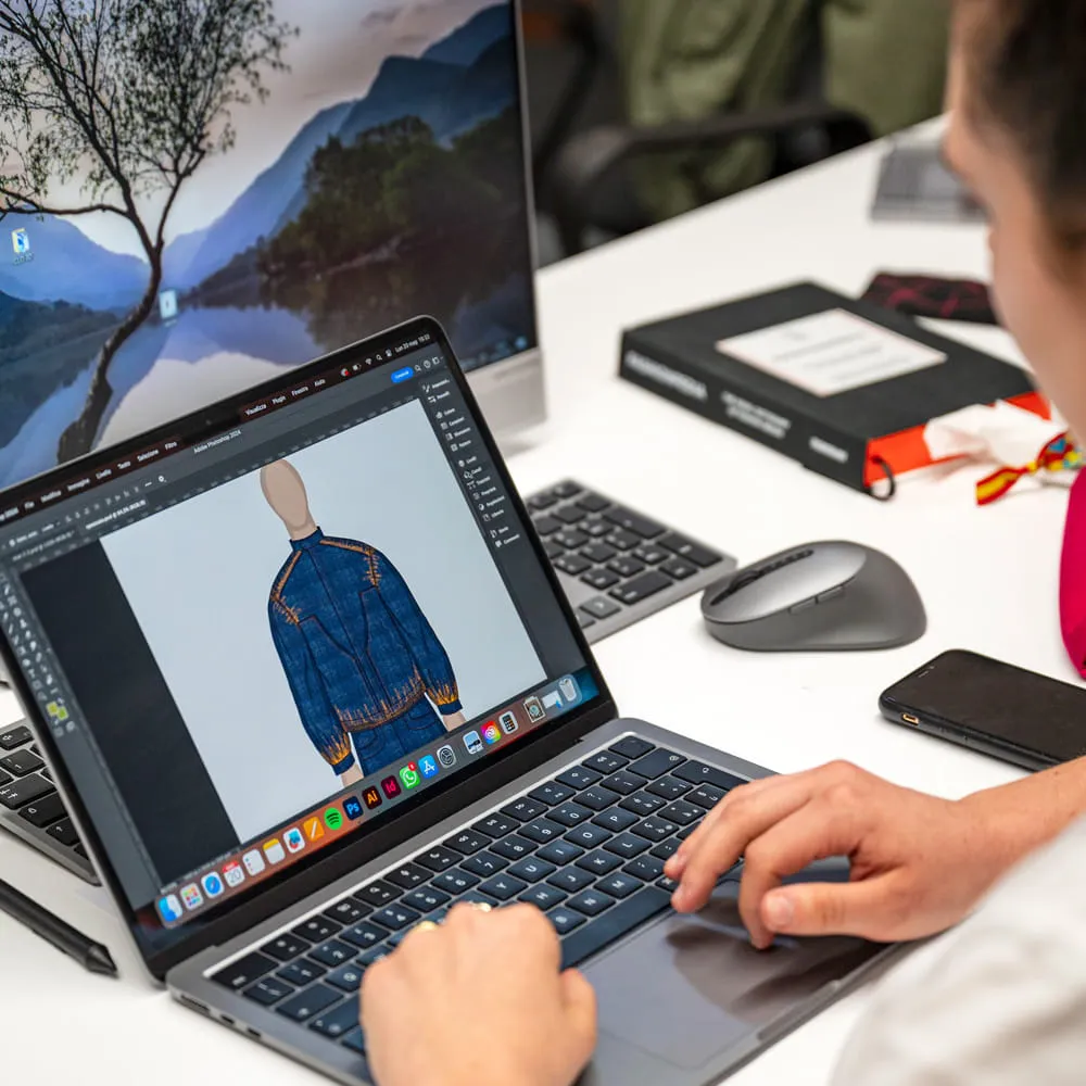 Studente al portatile che disegna il figurino di una giacca blu